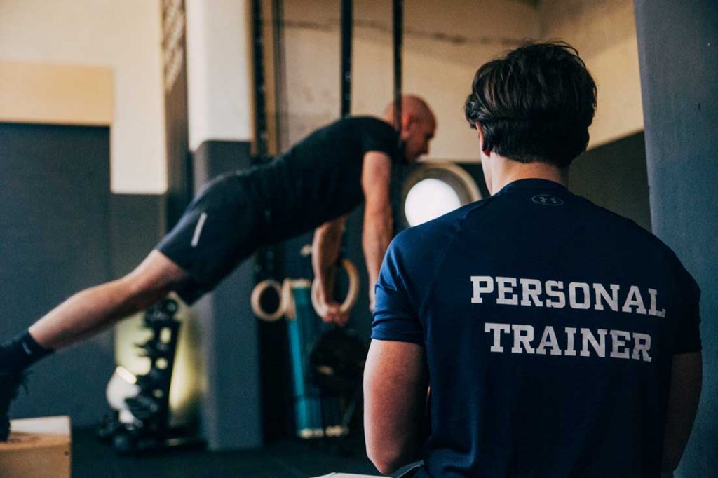 Personal trainer bekijkt sporter tijdens oefening