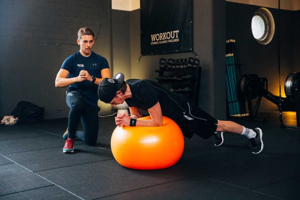 Man bezig met core training onder toezicht van personal trainer