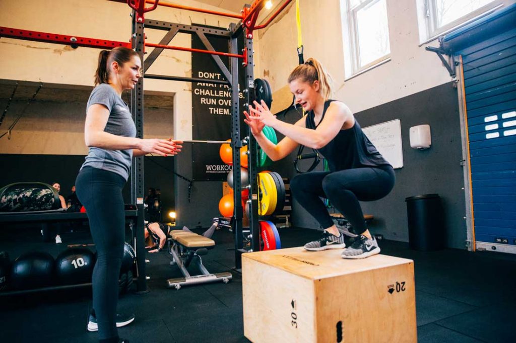 Vrouw aan het sporten onder toezicht van personal trainer